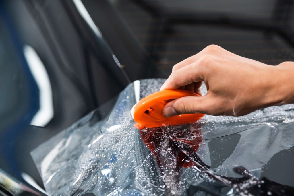 Profesional poniendo PPF en coche para proteger la pintura